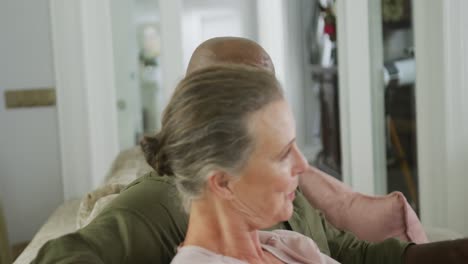 happy senior diverse couple wearing shirts and watching tv in living room