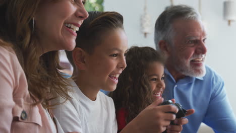 abuelos hispanos con nietos jugando videojuegos en casa sentados en el sofá juntos