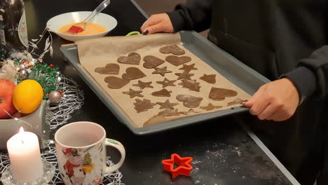 Women-up-close-taking-gingerbread-shapes-homemade-cookie-for-baking