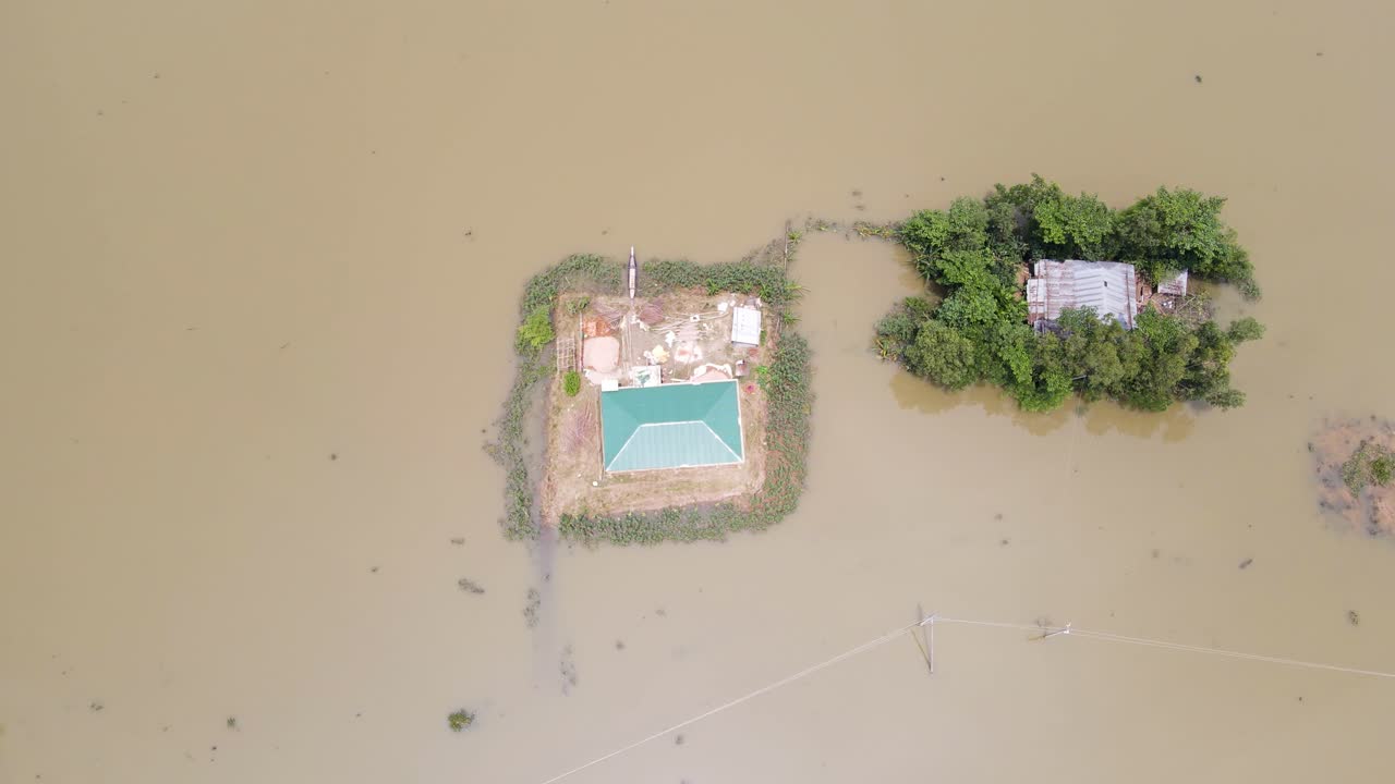 Dry home surrounded by flood in rural Bangladesh flood barrier home, aerial drone view