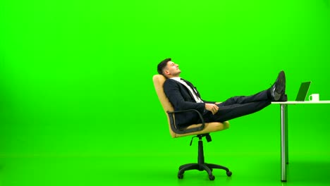 the handsome businessman relaxing at the table on the green background