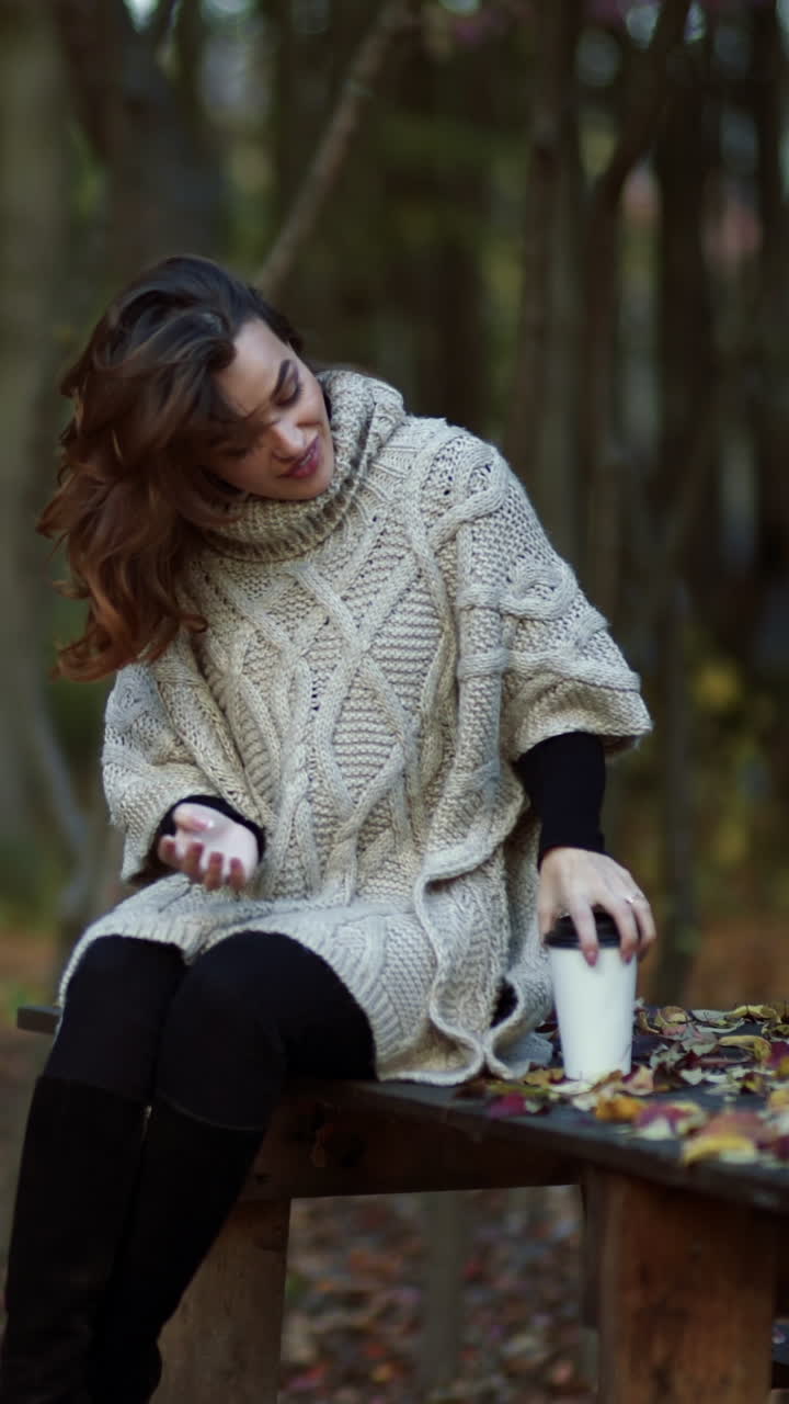 Woman spending time in park. Young woman spending time with cup of coffee in autumn park Vertical video