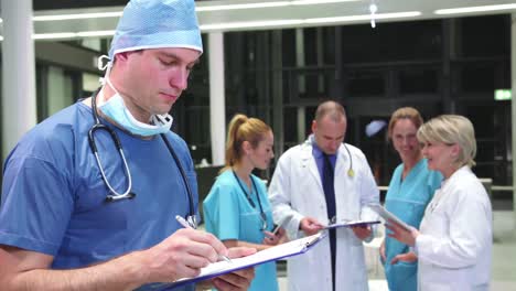 cirujano sonriente escribiendo en el clipboard en el pasillo del hospital