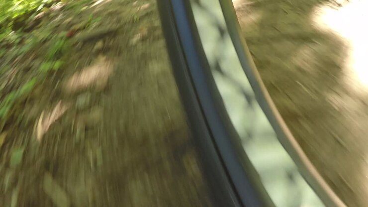 Low angle view of a bike tire moving over a dirt path.