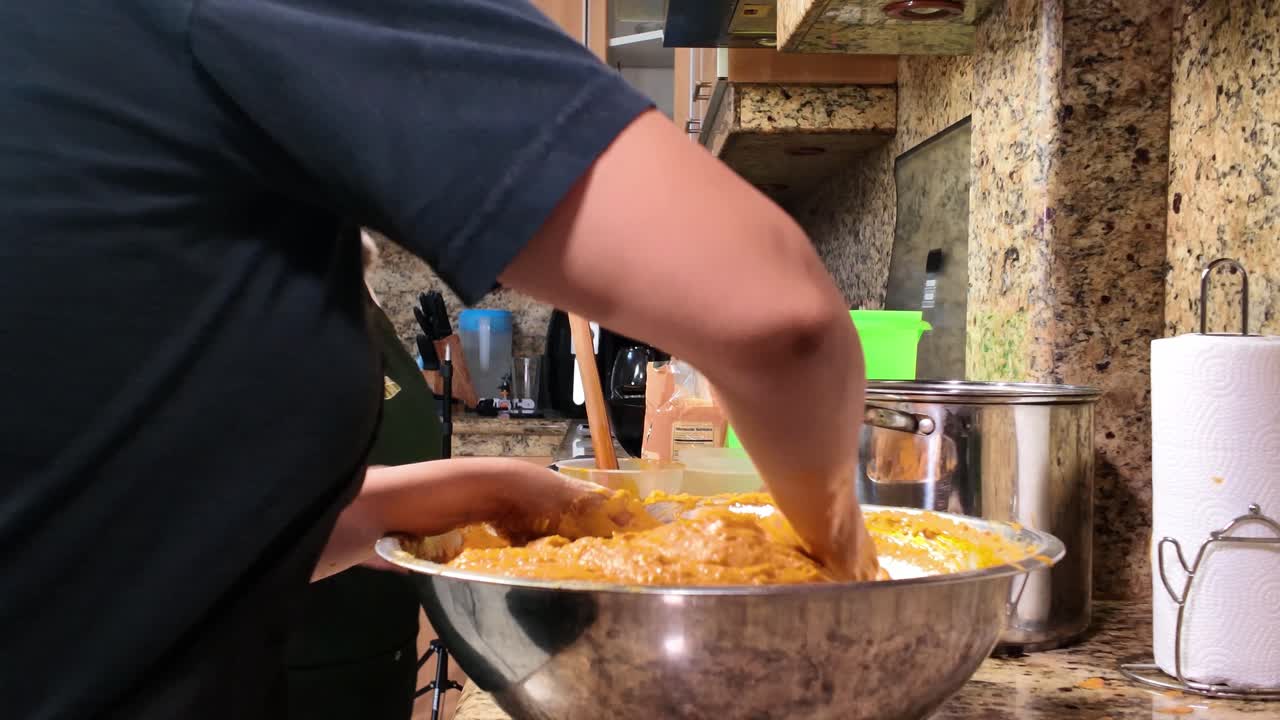 Vista laterale di donne che impastano masa di mais venezuelana in una cucina rustica, preparando le tradizionali hallacas.