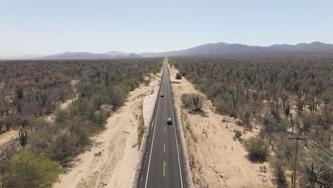 aerial: car driving on straight road through desert, long car journey