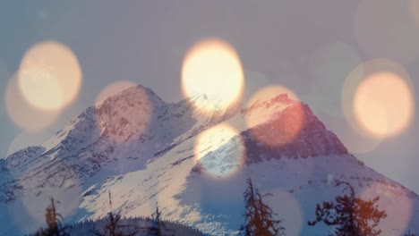 composite video of burning candle and spots of light against landscape with snowy mountains