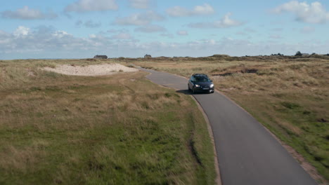 Seguimiento-Hacia-Atrás-De-La-Conducción-De-Automóviles-Por-El-Campo.-Estrecha-Carretera-Asfaltada-Que-Conduce-A-Los-Pastizales.-Dinamarca