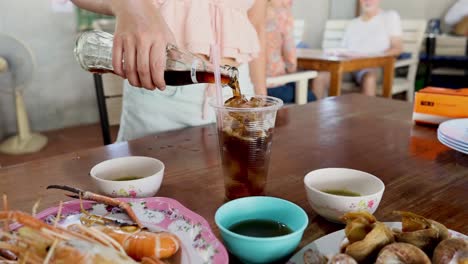 person pouring cola into a glass with ice