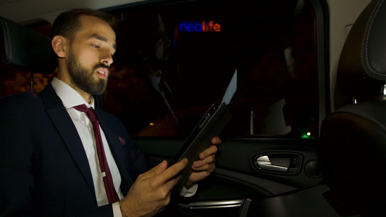 hombre de negocios durante una llamada de video de negocios en el asiento trasero de su coche de lujo