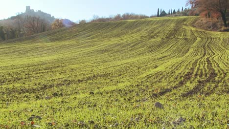 una toma amplia de la verde campiña italiana con un castillo distante que agrega misterio