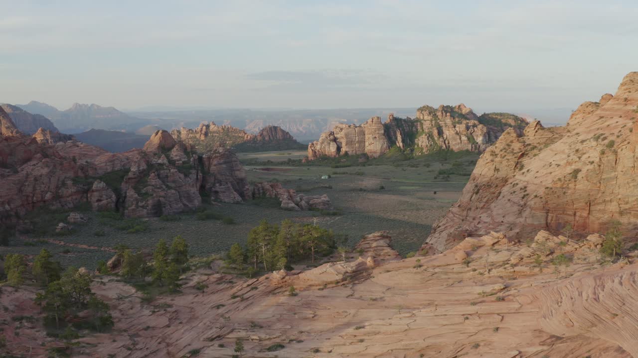 медленный пролет дрона над скалистыми утесами с видом на зеленые травянистые поля и величественные далекие скальные образования на территории национального парка сион