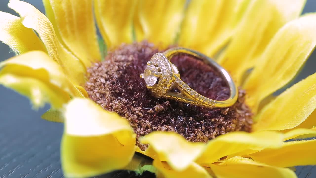Wedding ring placed on a sun flower with a light moving around it