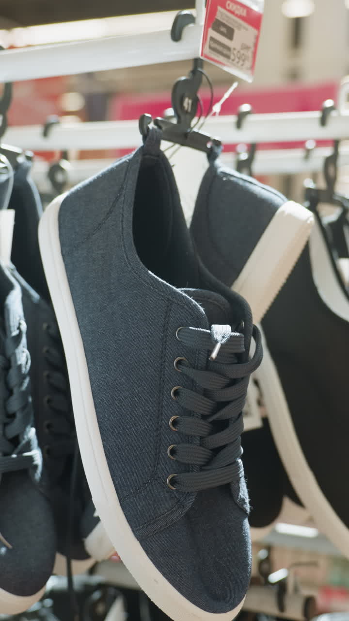 한 배경으로 쇼핑몰의 랙에 매달린 검은 신발의 클로즈업 뷰.이 비디오는 소매 환경에서 신발 디스플레이를 강조하여 다양한 스타일의 신발을 보여줍니다.