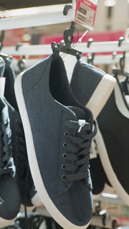 vista en primer plano de zapatos negros colgados en un estante en un centro comercial con un fondo borroso. este video destaca la exhibición de calzado en un entorno minorista, mostrando varios estilos de zapatos
