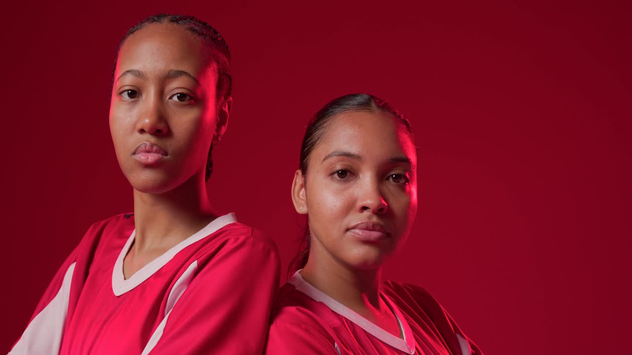 African American women leaning in clasping, sitting posing in studio for team promo in red jerseys