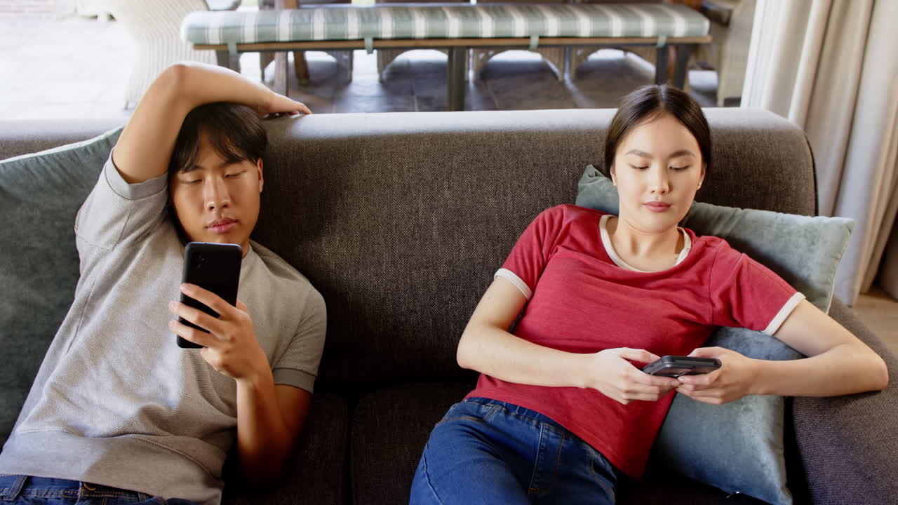 Relaxing on couch, couple using smartphones and unwinding at home