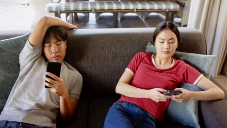 relaxing on couch, couple using smartphones and unwinding at home