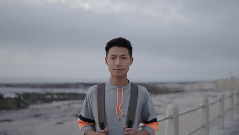 portrait of young asian man standing looking confident on beach