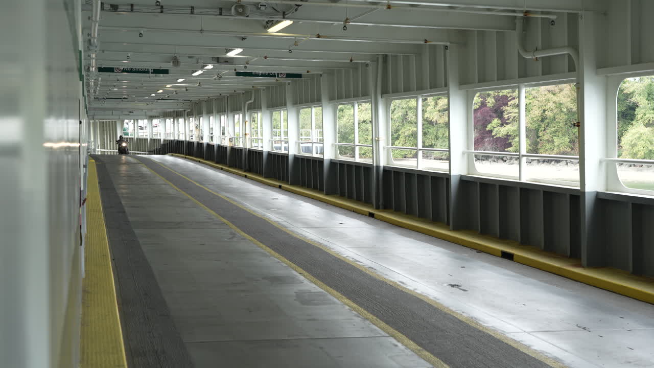 A motorcyclist rides onto a Washington State ferry, navigating the vehicle deck. The scene highlights transportation across the scenic waters of the Pacific Northwest.