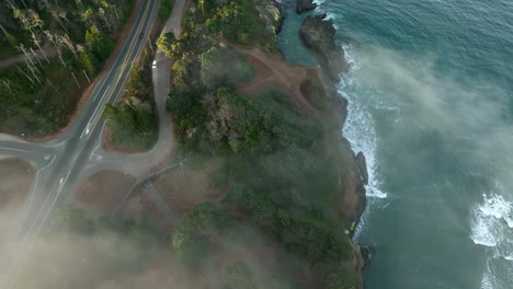 Aerial-view-of-fog-rolling-through-California's-scenic-highway-with-views-of-the-ocean