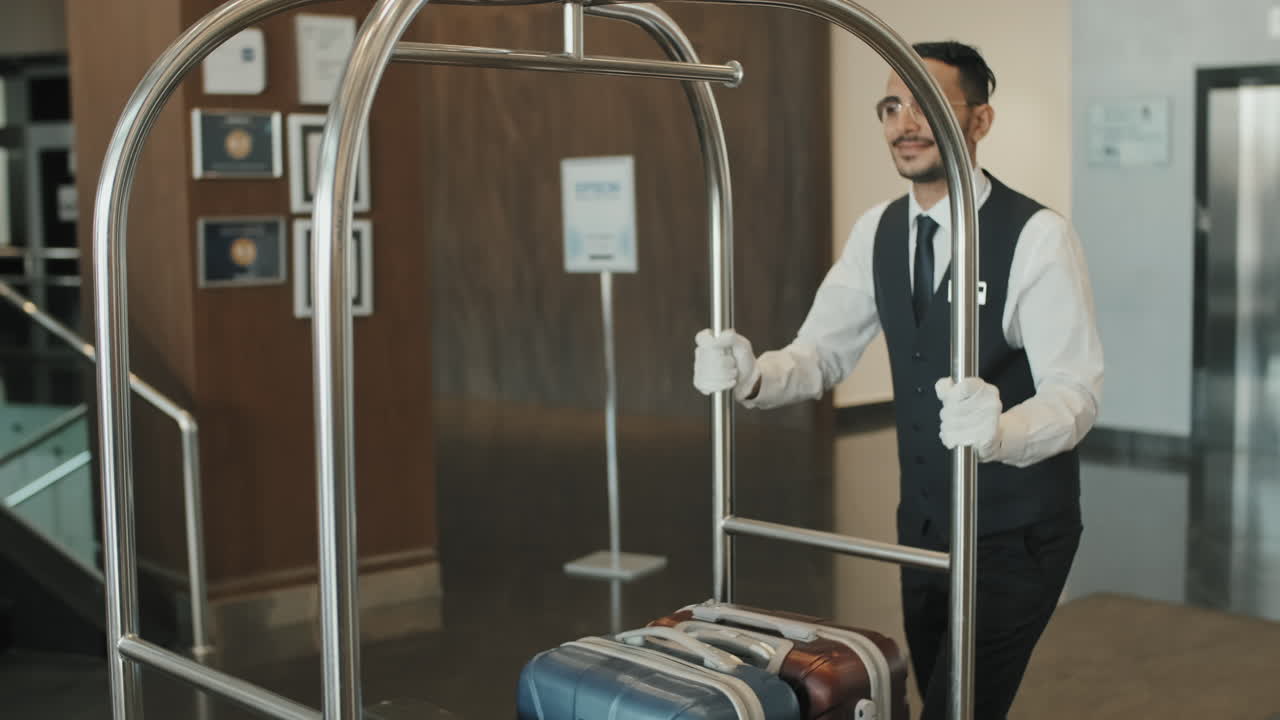 Cheerful Bellboy Carrying Luggage along Lobby