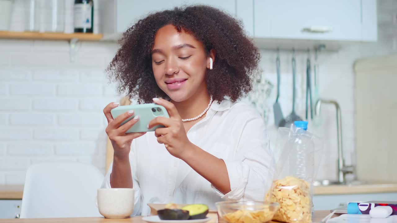 African american woman holds smartphone horizontally plays games online