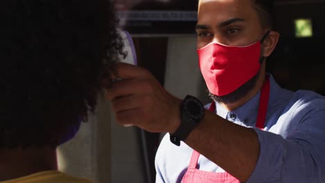 Trabajador-De-Café-De-Raza-Mixta-Con-Mascarilla-Tomando-La-Temperatura-De-Una-Compañera-De-Trabajo