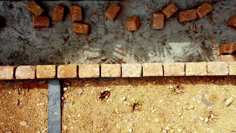 to cement the earth blocks close to the foundation, building the foundation of the house, workers work at a construction site in india, building a house with red stone , works using cement