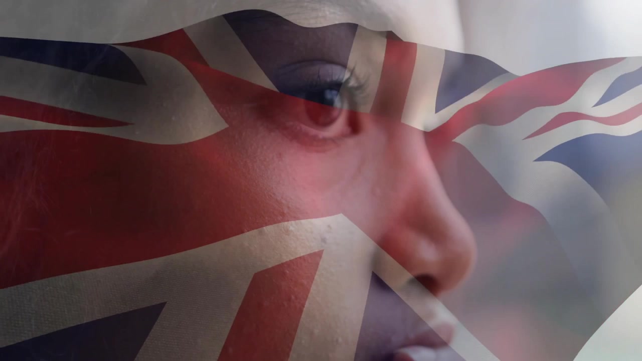 Donna seduta vicino alla finestra con lo sguardo fisso, che riceve una sovrapposizione della bandiera britannica che sventola sul viso, in un contesto educativo.