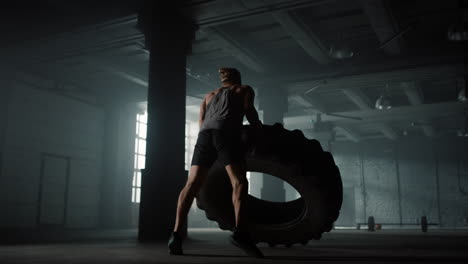 athlete preparing for strength exercise with rubber tire. man flipping tire