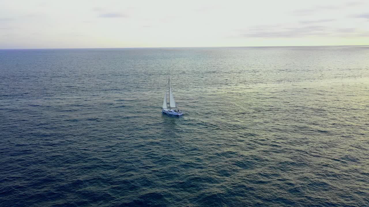 volando hacia un velero durante la puesta de sol de la hora dorada en el océano pacífico frente a la costa de marina del rey california