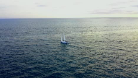 volando hacia un velero durante la puesta de sol de la hora dorada en el océano pacífico frente a la costa de marina del rey california