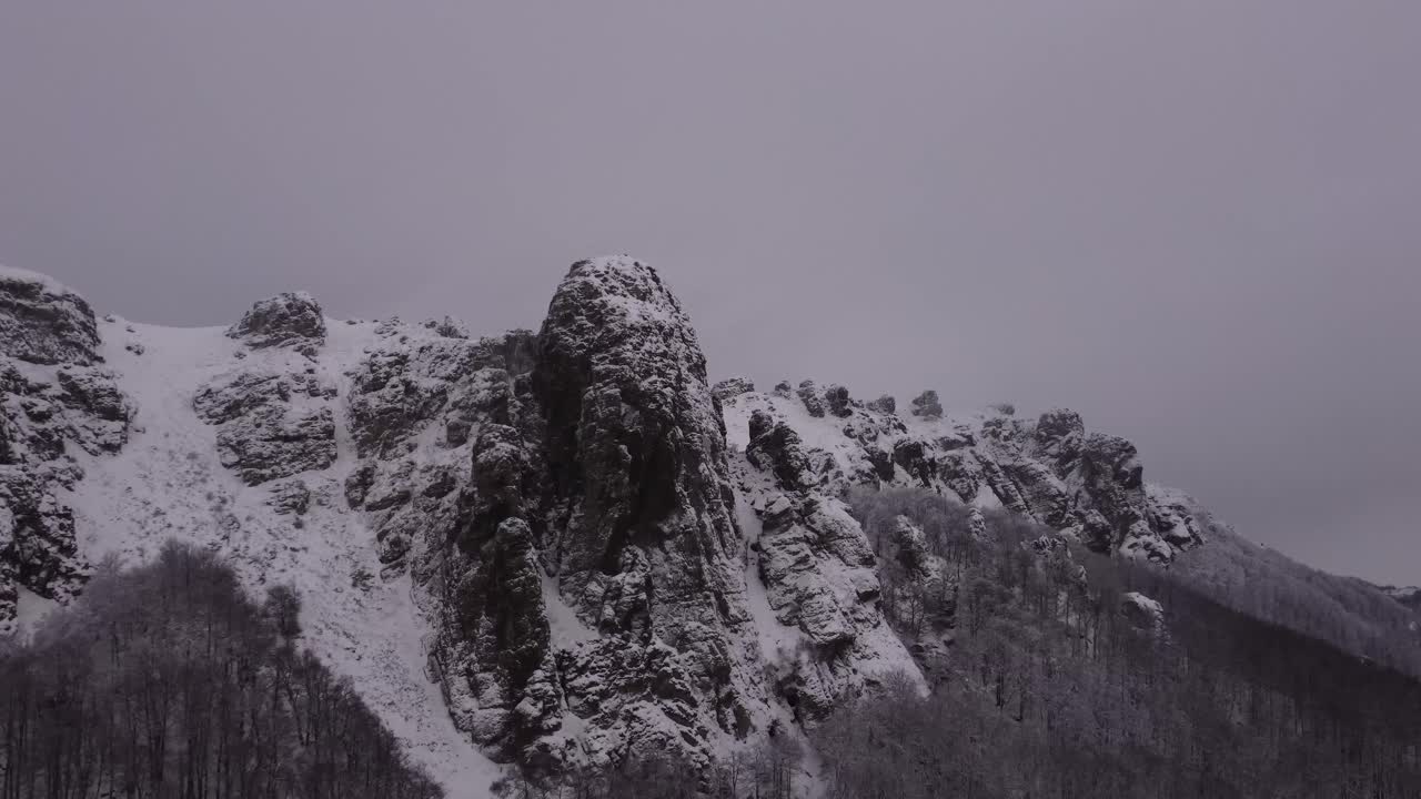 drone está escalando sobre el pico de la montaña rocosa en el invierno