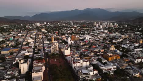 Aerial-view-tilting-over-the-cityscape-of-Santa-Marta,-sunny-evening-in-Colombia