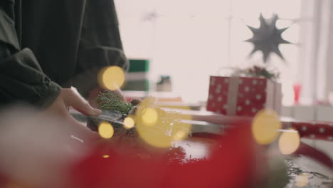 Crop-hands-decorating-wrapped-box-with-string.-Female-packing-cardboard-gift-box-on-wooden-table-with-various-decorative-items-prepared-for-Christmas-celebration.-Detail-female-hands-tying-rope