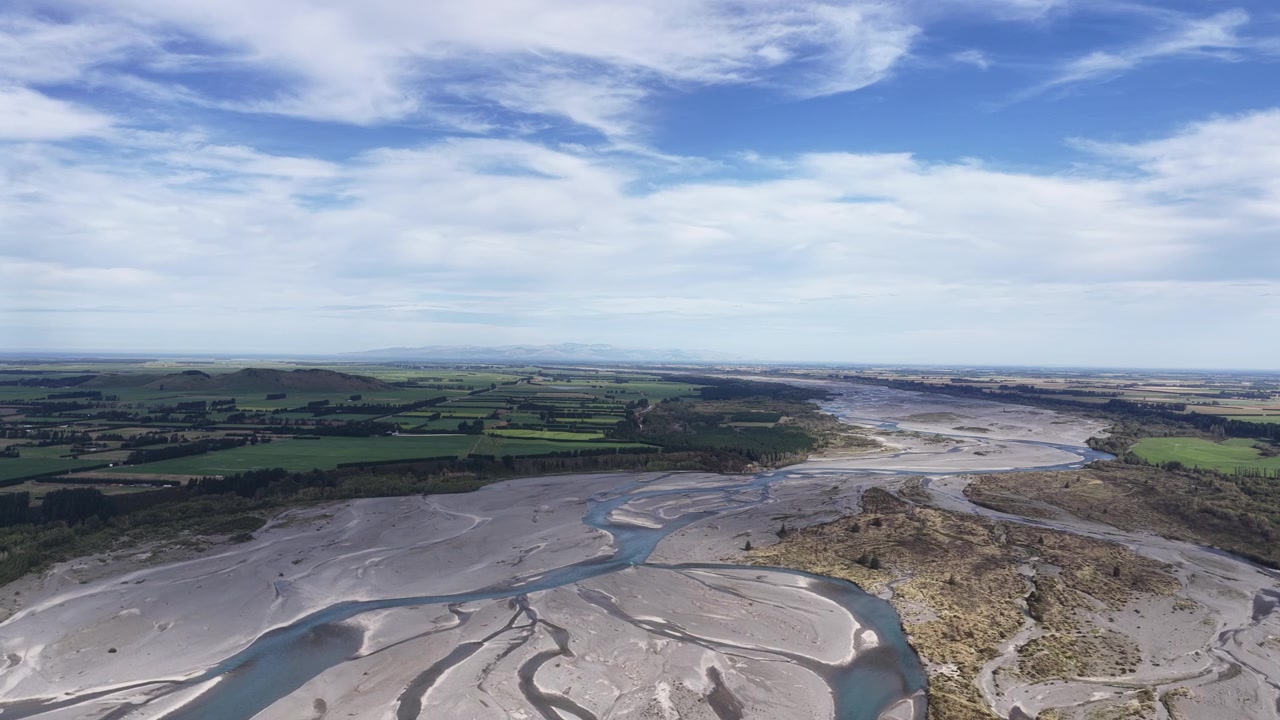 Panorama aereo di un sistema fluviale a canali intrecciati che attraversa vaste pianure sull'Isola del Sud della Nuova Zelanda, rivelando schemi naturali modellati dall'acqua che scorre e dai depositi di sedimenti.