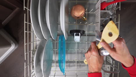 man loading dirty silverware utensils into the dishwasher for cleaning