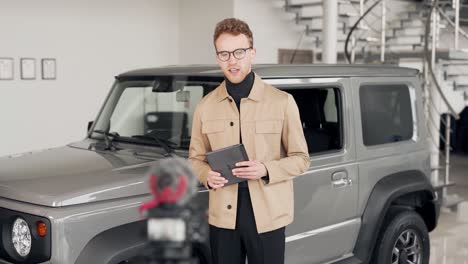 handsome young man in a car dealership talks about the car filming everything on video