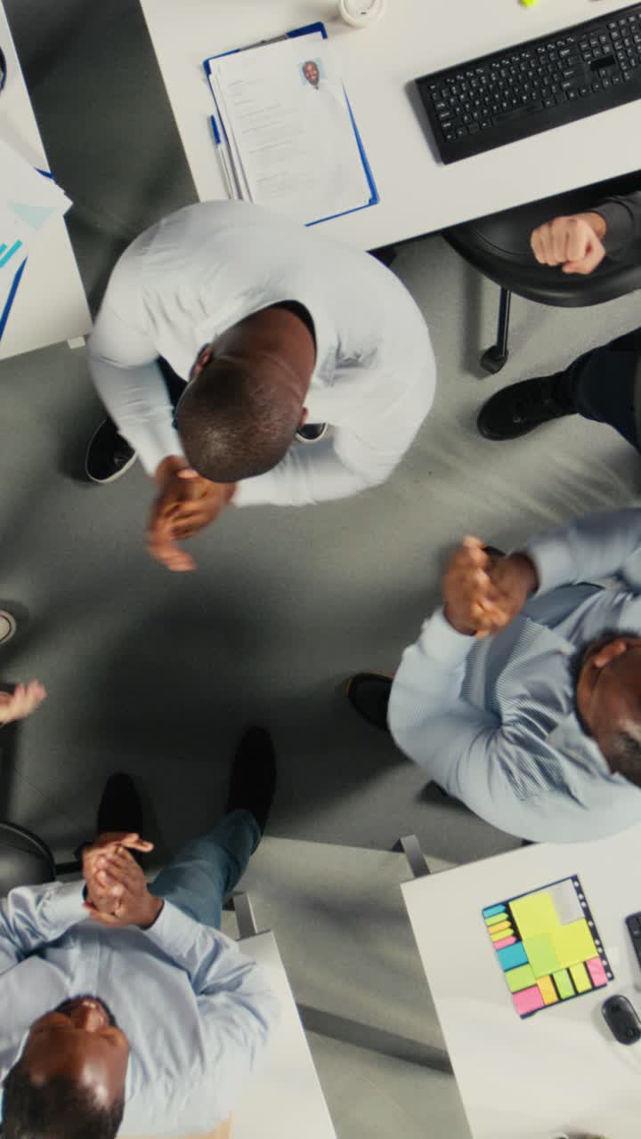 Lodret video. Top-down view zoomer ind på personale, der er stolte af deres succesfulde teamwork