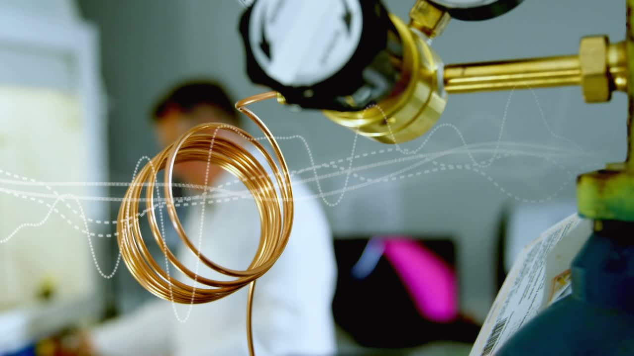 Lab tech responding to gauge, inspecting hood, noting readings with waveform over coil