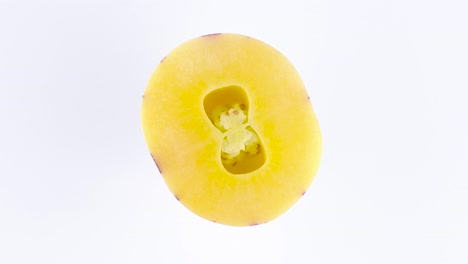 top view from above of a cut in half mature yellow pepino. rotating on the turntable isolated on the white background. close-up. macro.