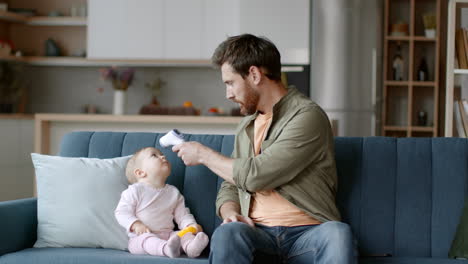 father checking baby's temperature at home