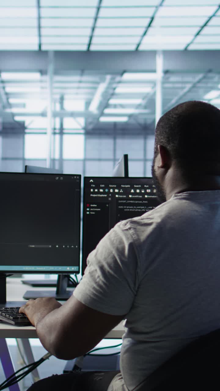 African American Man Coding on Multiple Computer Screens in Office