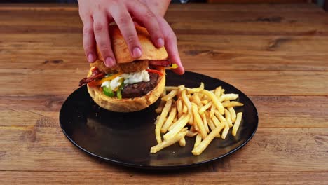 Close-up-of-a-lamb-burger-with-french-fries-being-picked-up-and-opened-to-show-the-delicious-ingredients