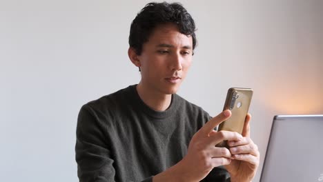 자신의 전화로 자신의 컴퓨터 사진을 찍는 혼혈 아시아인과 유럽인