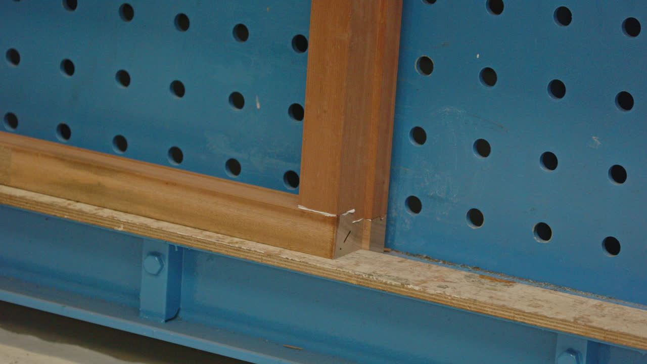Primo piano degli angoli di una cornice di legno uniti da una pressa meccanica