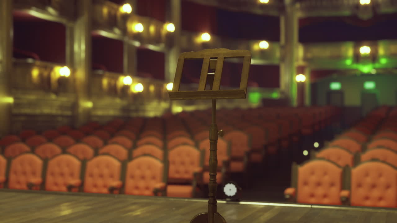 Empty theater stage awaits performance with illuminated seating area