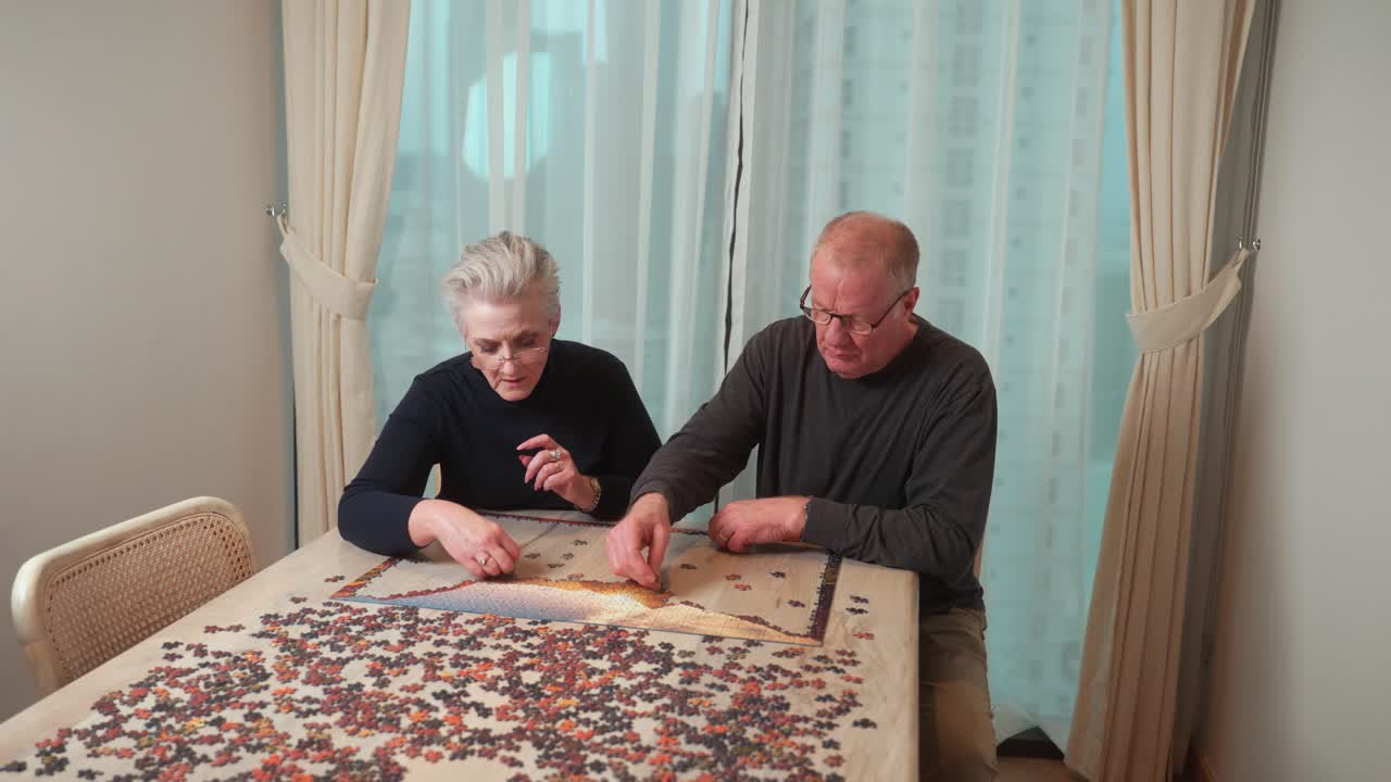 Couple enjoying senior years together and cooperating by putting a puzzle together in their golden years