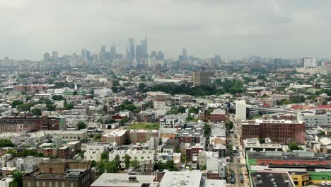 Barrios-De-Kensington-Y-El-Norte-De-Filadelfia-Con-El-Horizonte-De-Filadelfia-En-La-Distancia,-Toma-Aérea-De-Establecimiento-De-Comunidades-Pobres,-Hogares-Y-Proyectos-De-Vivienda,-Día-De-Verano